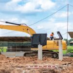 Mechanic performing engine maintenance on an excavator at a job site