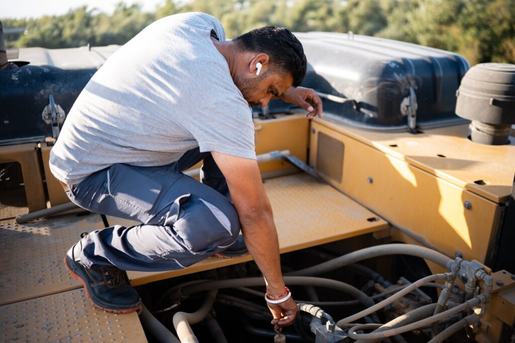Mechanic servicing an excavator engine outdoors