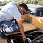 Mechanic servicing an excavator engine outdoors