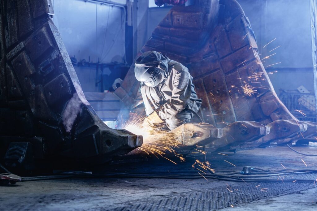 Welder cutting a large excavator bucket in the fabrication shop