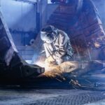 Welder cutting a large excavator bucket in the fabrication shop