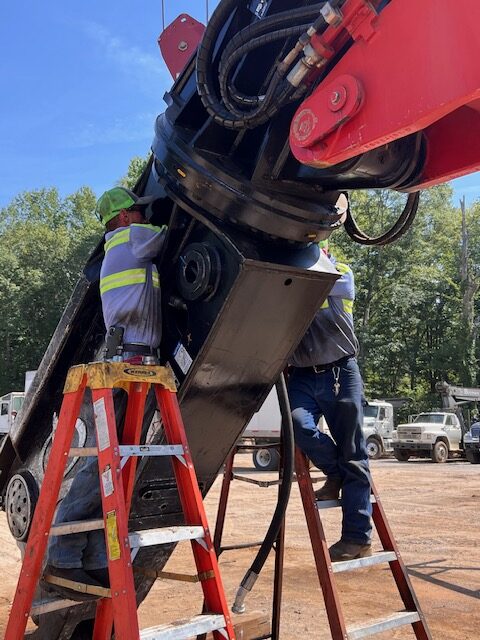 Two Heavy Equipment Repair mechanics servicing a hydraulic attachment in Carrollton, GA